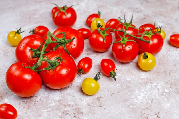 Arrangement of colorful fresh assorted tomatoes on concrete surface