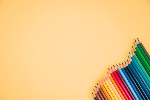 Arrangement of colorful pencils at the corner of yellow backdrop