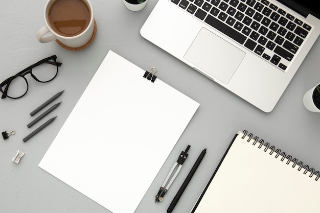 Arrangement of desk elements with empty notebook on grey background