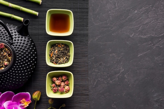 Arrangement of dried flower and tea herb on black place mat over background