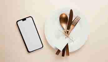Free photo arrangement of elegant tableware with empty smartphone