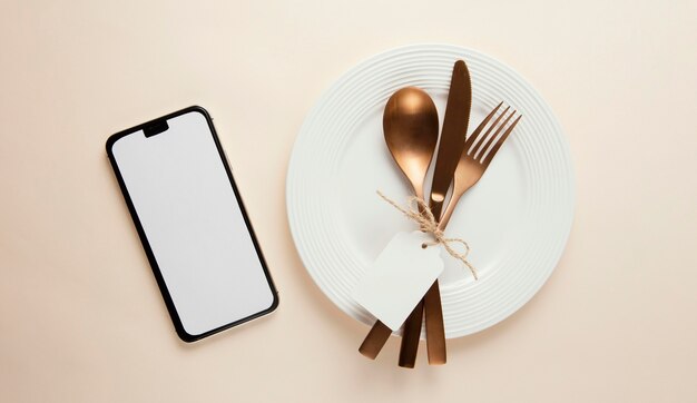 Arrangement of elegant tableware with empty smartphone