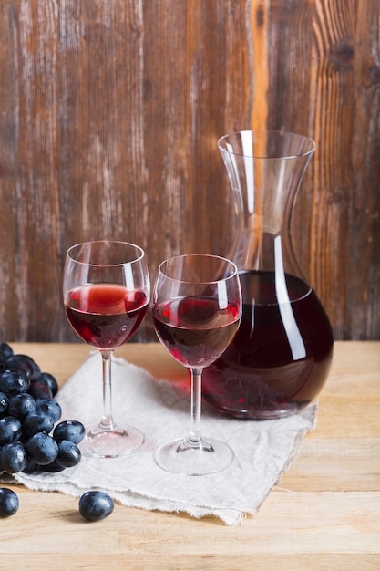 Arrangement of glasses and carafe of wine on wooden background