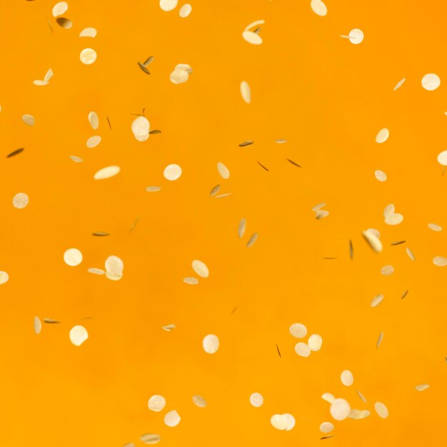 Arrangement of golden party confetti on orange wall