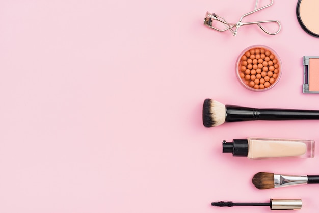 Arrangement of makeup products on pink background