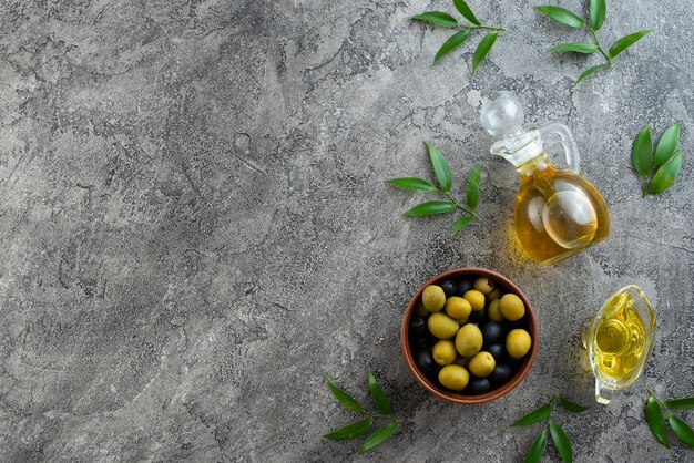 Arrangement of olives and oils on marble background