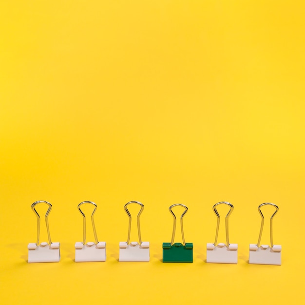 Free photo arrangement of paper clips with one green paper clip