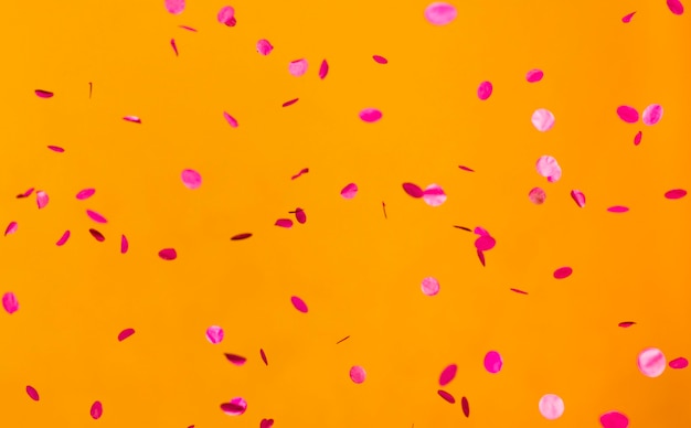 Arrangement of party red confetti on orange wall