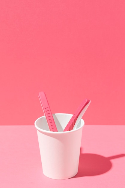 Arrangement of pink razor blades and cup