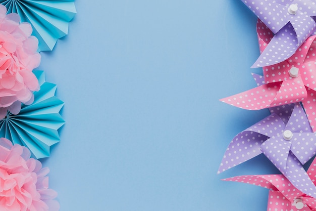 Free photo arrangement of pinwheel and beautiful flower cutout over blue background