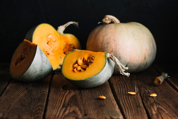 Arrangement of pumpkins and slices on wooden background