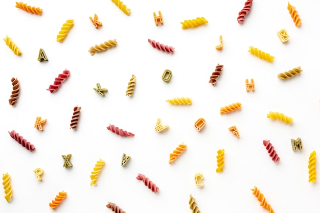 Arrangement of uncooked colorful fusilli and alphabet pasta