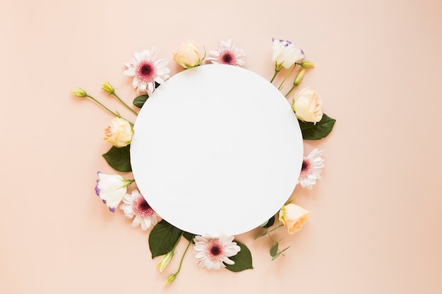 Arrangement of various spring flowers and empty round piece of paper