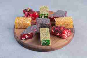 Free photo an arrangement of various turkish delight flavors on a wooden board on marble background.