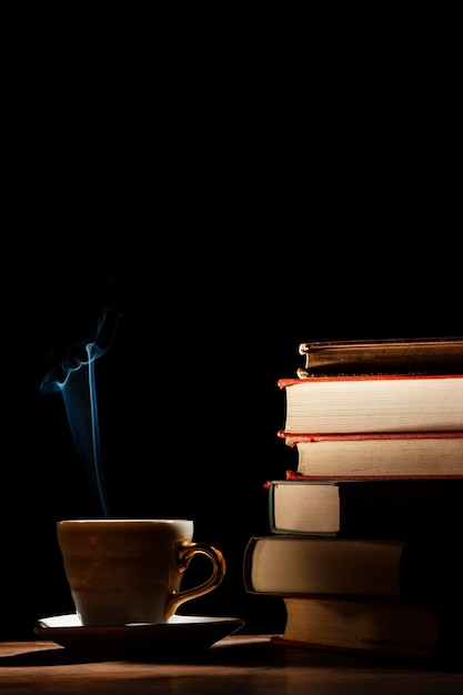 Arrangement with books, cup and dark background