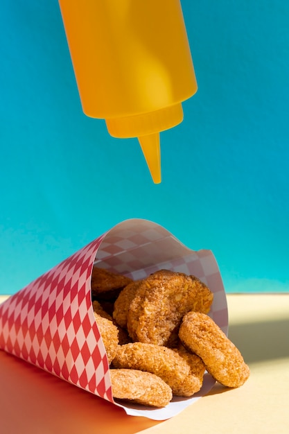 Free photo arrangement with bottle of mustard and nuggets