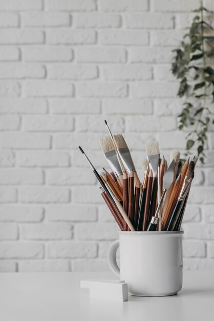 Arrangement with brushes and pens in cup