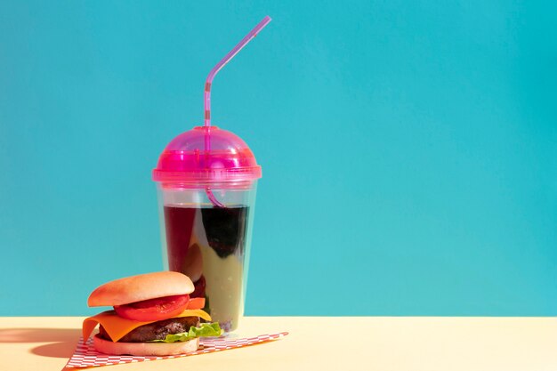 Arrangement with cup of juice and cheeseburger