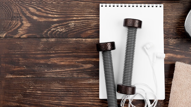 Free photo arrangement with dumbbells and notebook