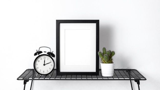 Free photo arrangement with empty black frame next to clock