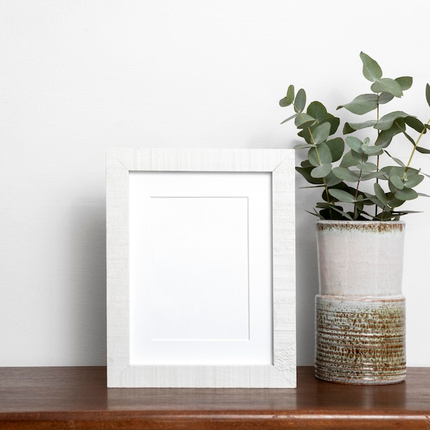 Arrangement with empty black frame next to plant