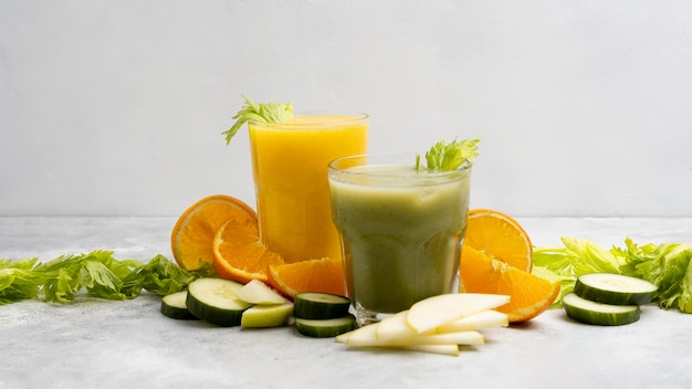 Free photo arrangement with green and orange juices