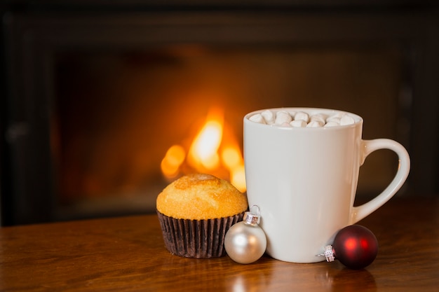 Arrangement with marshmallow drink and muffin near the fireplace