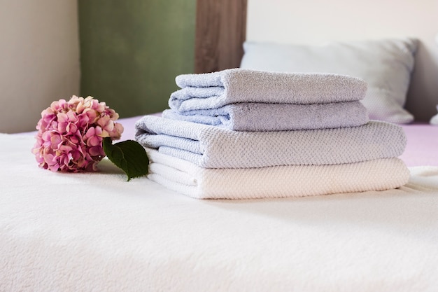 Arrangement with pink flower and towels on bed