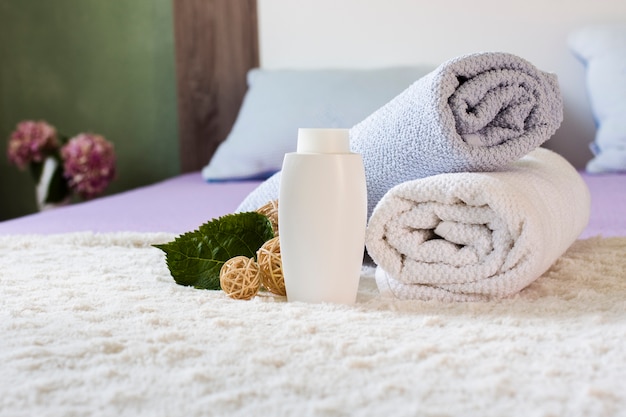 Free photo arrangement with white bottle and towels on bed