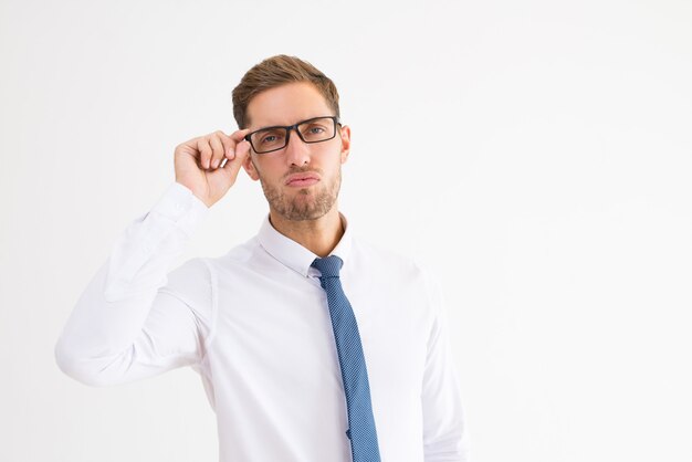 Arrogant business man adjusting glasses and looking at camera