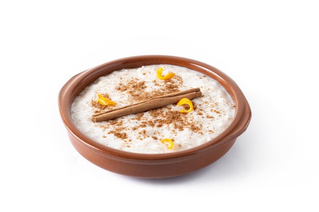 Arroz con leche Рисовый пудинг с корицей в глиняной миске, изолированной на белом фоне