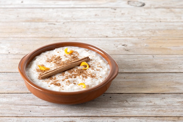 Arroz con leche 나무 테이블에 있는 점토 그릇에 계피를 넣은 라이스 푸딩