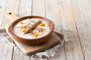 Free photo arroz con leche rice pudding with cinnamon in clay bowl on wooden table