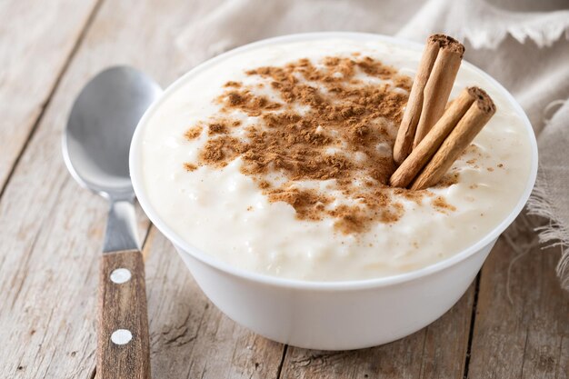 Arroz con leche Rice pudding with cinnamon in clay bowl on wooden table