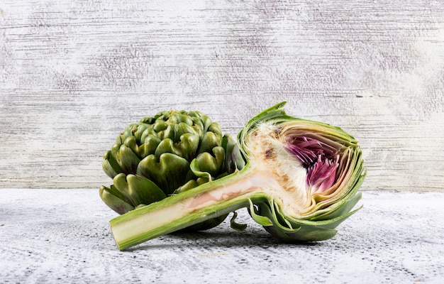 Artichoke and slice side view on a light gray  space for text