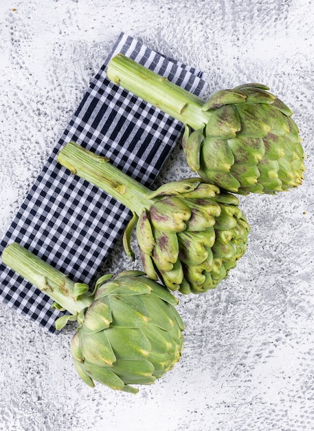 Artichokes top view on a picnic cloth and light gray 