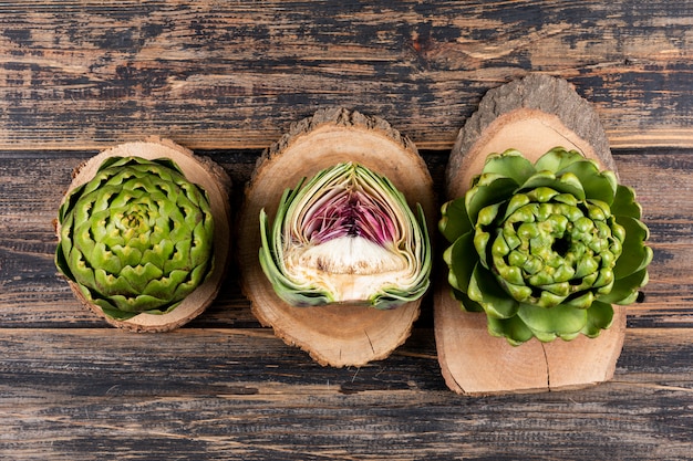 Free photo artichokes top view on small stubs and dark wooden