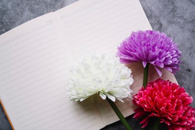 Artificial chrysanthemum flowers on an open single line notebook