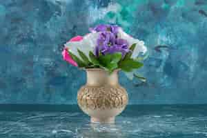 Free photo artificial colorful flower in a vase , on the blue background.
