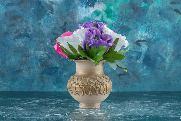 青い背景に、花瓶に人工のカラフルな花。