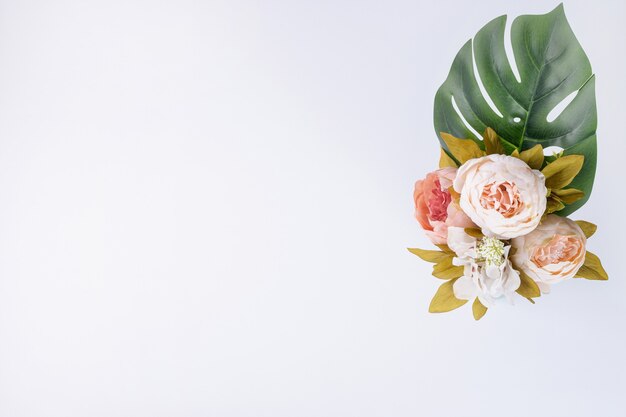 Artificial leaf and bouquet of flowers on white surface.