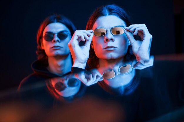 Artificial lighting. Portrait of twin brothers. Studio shot in dark studio with neon