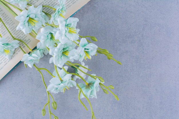 Foto gratuita fiore artificiale del giglio di madonna disposto sul libro aperto