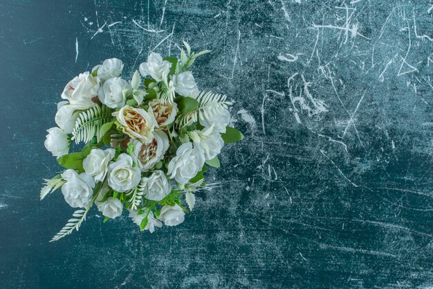青い背景に、花瓶に人工の白い花。
