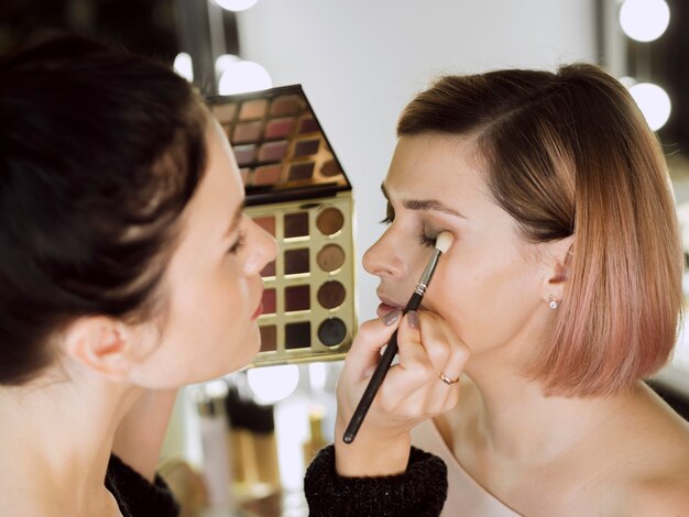 Artist applying eye shadow on client