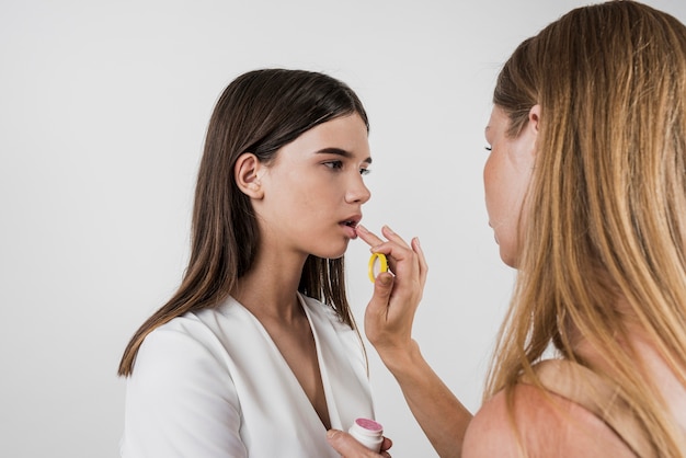 Free photo artist applying lip balm on model