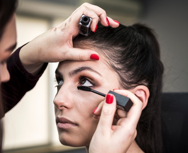 Artist applying mascara on cute model