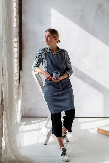 Free photo artist in apron posing with mug