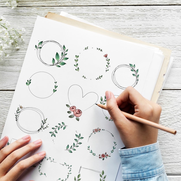 Artist drawing doodle floral wreaths on a paper
