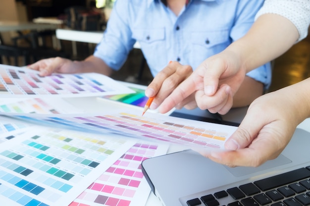 Artist drawing on graphic tablet with color swatches in office.